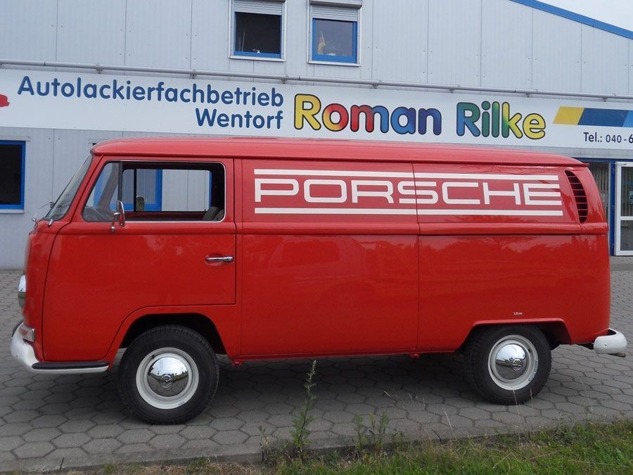 VW Bus T2 in rot mit einer Porsche Aufschrift in weiß.