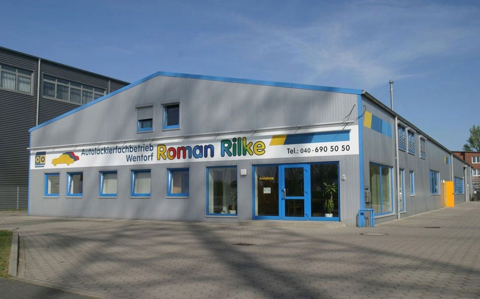 Graues Firmengebäude von Roman Rilke mit farblich passenden blauen Akzenten.